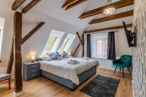 a bedroom with a large bed and a blue chair at Fulop Panzio Rooms in Révfülöp