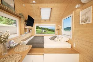 a bedroom in a tiny house with a bed and windows at Aurora Green Hill in Podobin