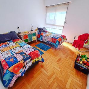 Un dormitorio con dos camas y suelo de madera. en Departamento Centro Bahía, en Bahía Blanca