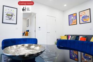 a living room with a table and a blue chair at 2 Bedroom Apartment By Littlepiggyrentals Short Lets & Serviced Accommodation Stevenage With Free Parking, Gym & Roof Garden in Stevenage