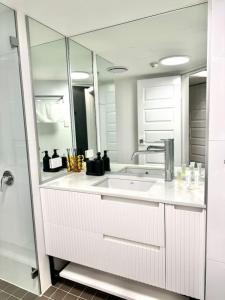 a white kitchen with a sink and a mirror at Stylish Family 1BR with Cozy Bunks and Games for 5 in Sydney