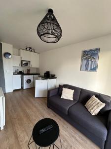 a living room with a couch and a table at Appartement Cosy, 400m plage proche centre ville in Cabourg