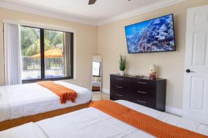 a bedroom with two beds and a tv on the wall at 4-min Walk to Beach Pool Tiki Canal Boat Dock in Deerfield Beach +58 photos