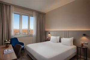a hotel room with a large bed and a desk at NH Trieste in Trieste