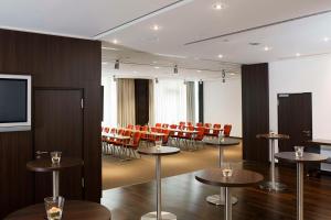 a conference room with tables and chairs and a screen at NH Collection Berlin Mitte Friedrichstrasse in Berlin