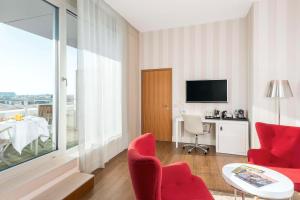 a living room with red chairs and a table at NH Collection Berlin Mitte Friedrichstrasse in Berlin