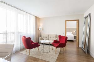 a living room with red chairs and a couch at NH Collection Berlin Mitte Friedrichstrasse in Berlin
