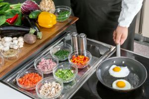 a person preparing food in a kitchen with vegetables at NH Collection Berlin Mitte Friedrichstrasse in Berlin