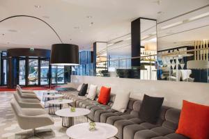 a lobby with a couch and tables and chairs at NH Collection Berlin Mitte Friedrichstrasse in Berlin