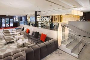 a lobby with couches and tables and a bar at NH Collection Berlin Mitte Friedrichstrasse in Berlin
