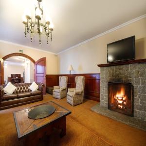 a living room with a fireplace and a television at Hotel Chateau in Campos do Jordão