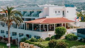 a view of a hotel with a palm tree at Vrachia Beach Hotel & Suites - Adults Only in Paphos