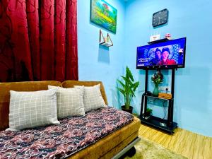 a living room with a bed and a flat screen tv at HH Homestay Dungun in Kampong Gok Kapor