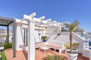 una casa blanca con un banco y una palmera en Breathtaking Penthouse Las Azaleas, en Torrox