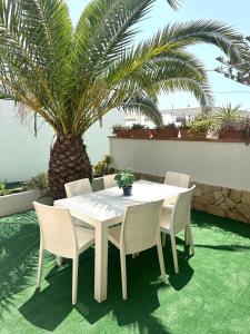 a white table and chairs on a patio with palm trees at Case vacanze ''Estremo Sud'' Lampedusa in Lampedusa