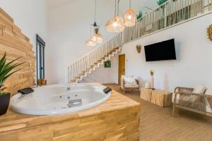 a large room with a large tub and a tv at La Suite Corse avec Spa in Lavilletertre