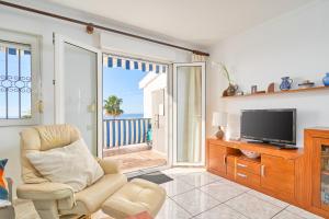 Una sala de estar con un televisor y una silla. en Sea View Capistrano Nerja, en Nerja