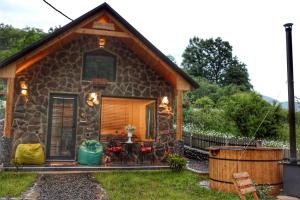 a small stone cottage with a porch and a patio at Woodlandia Borjomi with Hot Tub and Private Garden in Borjomi