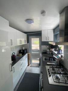 a kitchen with white cabinets and a stove top oven at The Bolthole in Nailsworth +4 photos