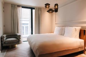 a bedroom with a bed and a chair and a window at The Diamond Amsterdam in Amsterdam