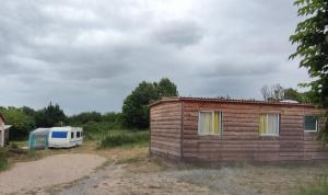 a small building next to a trailer and a truck at Belle caravane au calme in Persac