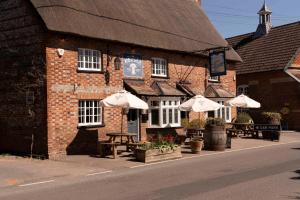 a building with tables and umbrellas in front of it at The Wheatsheaf in Chilton Foliat