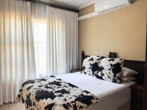 a bedroom with a bed with black and white sheets and a window at Tshamani self catering in Hazyview
