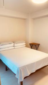 a bedroom with a bed with white sheets and pillows at SkyHotel Kikukawa 駅徒歩2分 in Tokyo