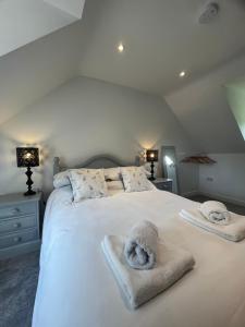 a bedroom with a white bed with towels on it at Woodpecker Lodge in Frampton