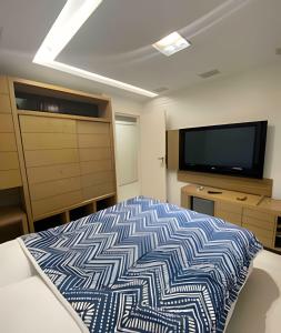 a bedroom with a bed and a flat screen tv at 3 Dorm. Frente Mar com Churrasqueria #16 in Balneário Camboriú