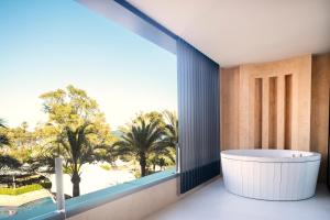 a bath tub in a room with a large window at Insotel Fenicia Prestige Suites & Spa in Santa Eularia des Riu