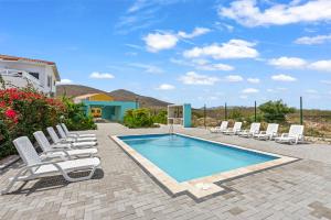 a group of chairs and a swimming pool with chairs and a house at Apartement Punta Azul 6A, Punta Azul Ocean Resort, Westpunt in Westpunt