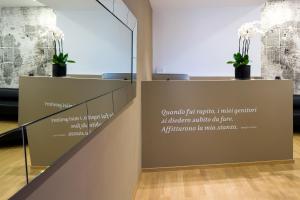 Mercatovecchio Luxury Suites في أوديني: علامة في غرفة مع نباتات الفخار على الحائط