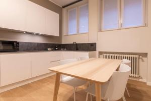 una cucina con un tavolo di legno e mobili bianchi di Grancini Suite a Milano Altre 37 foto