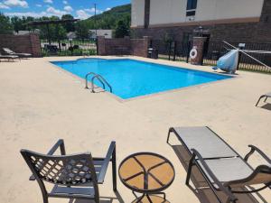 a swimming pool with two chairs and a table and a table and chairs at Holiday Inn Express and Suites Heber Springs by IHG in Heber Springs