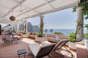 een terras met tafels en stoelen en uitzicht op de oceaan bij Villa Bella Vista in Capri