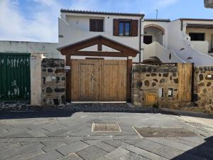 オロゼーイにあるGiove Rubea - Appartamenti in pieno centro storico a Oroseiの木の扉が前にある家