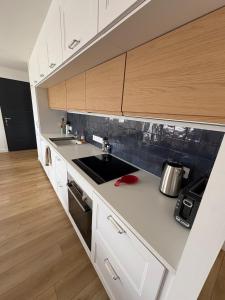 a kitchen with white counters and wooden cabinets at Casa Côme - Maison climatisée - Tout à pied ! in Saint-Vincent-sur-Jard
