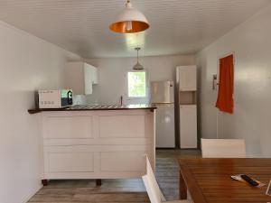 a kitchen with white cabinets and a table in a room at Hôtel Le Soleil Levant in Capesterre