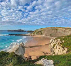 a beach with rocks and the ocean on a cloudy day at La casa de Cudón in Cudón