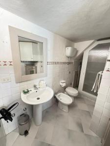 a white bathroom with a sink and a toilet at La Casetta sul Porto in Porto Ercole