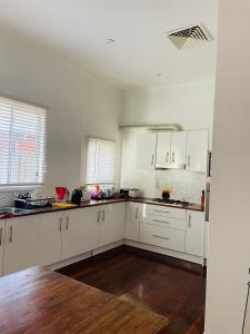 an empty kitchen with white cabinets and wooden floors at Cozy and Peaceful home surrounding by cafes and restaurants in Perth +6 photos