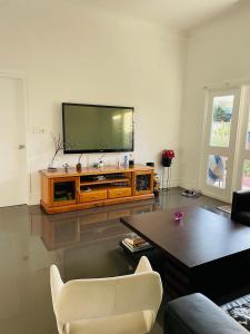 a living room with a flat screen tv on a entertainment center at Cozy and Peaceful home surrounding by cafes and restaurants in Perth