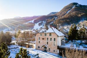 a building in the snow with a mountain in the background at Auberge de Jeunesse HI Serre-Chevalier in La Salle Les Alpes