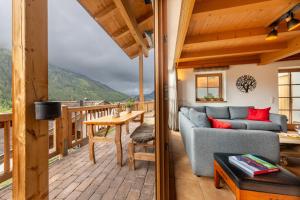 a living room with a couch and a table on a deck at Schöneben Chalet Steinlinge in Wald im Pinzgau