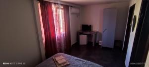 a bedroom with a bed and a window with a red curtain at Vila Hera in Eforie Sud