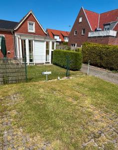 a yard with a fence in front of a house at Ferienwohnung Charly in Carolinensiel