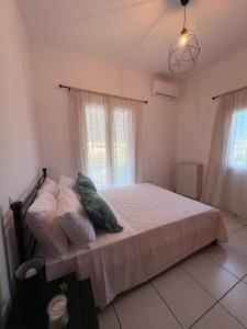 a bedroom with a bed with white sheets and pillows at Irène House in Egina