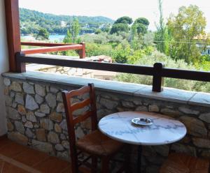 a stone wall with a table and two chairs and a window at Villa Maraki in Agia Paraskevi