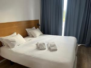 a large white bed with two books on it at Sintra Sol - Apartamentos Turisticos in Sintra